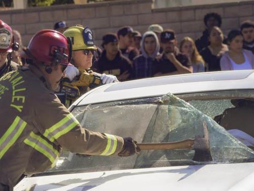 Firefighters breaking a windshield to help a driver 