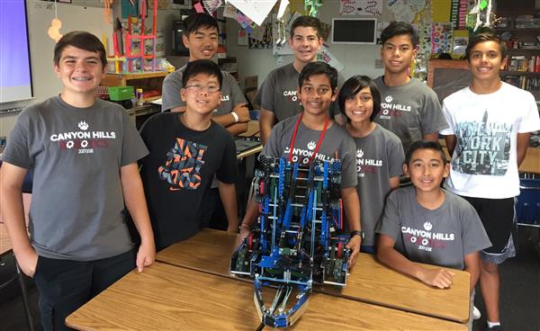 Photo of eight junior high age boys behind a robot they made